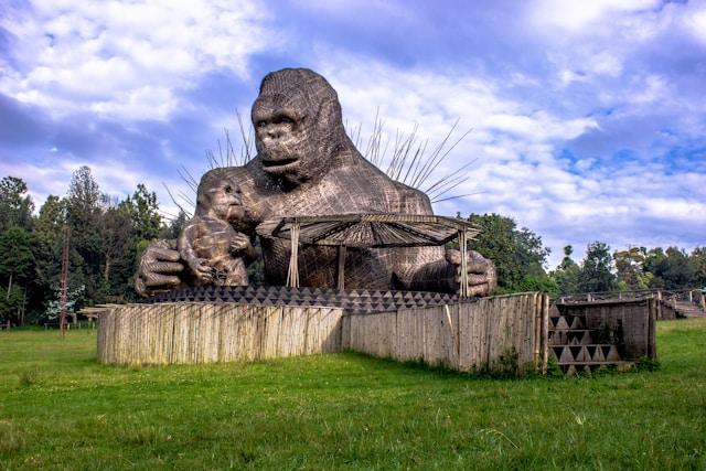 A large statue of a gorilla sitting in a green field.