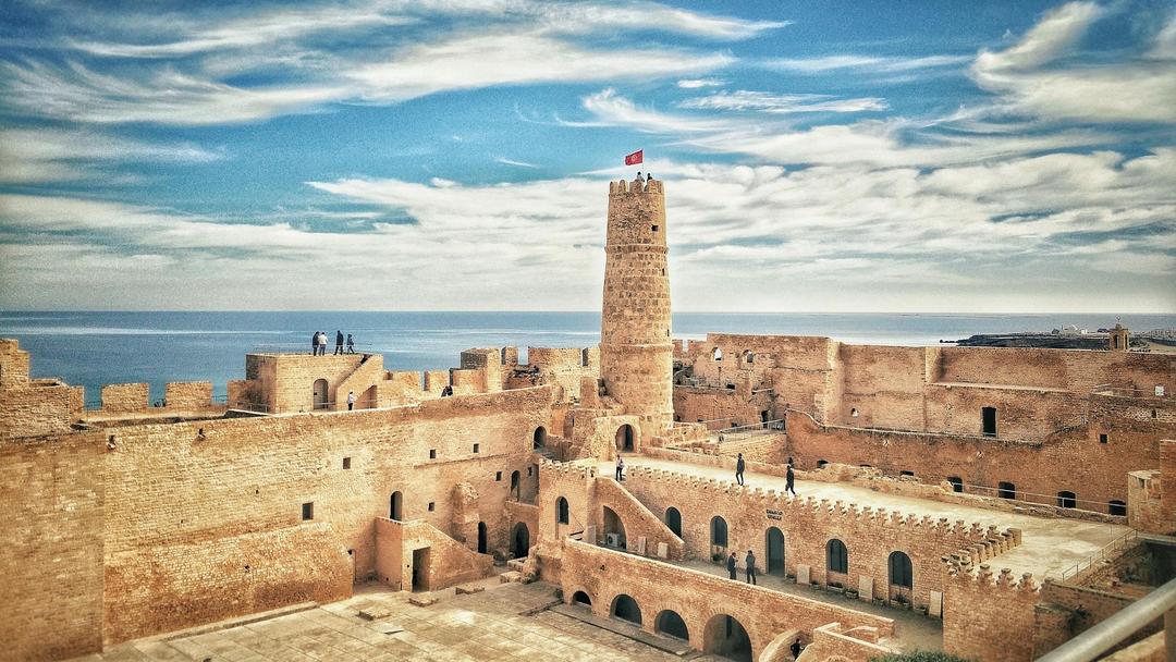 The Ribat of Monastir in Tunisia, depicted by a stone castle in front of the sea.